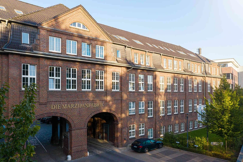 Historisches Backsteingeb&auml;ude der Oberberg Fachklinik Marzipanfabrik mit Torbogen und Innenhofzufahrt bei Tageslicht.