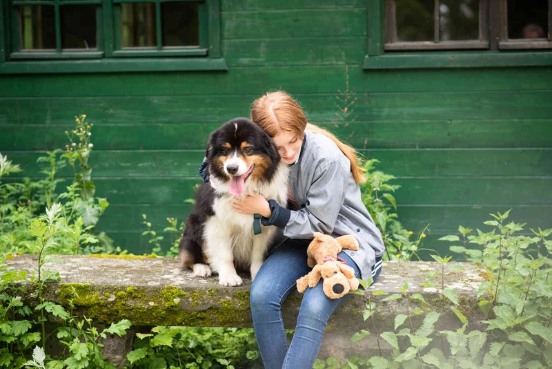 Frau sitzt mit einem Hund drau&szlig;en l&auml;chelnd