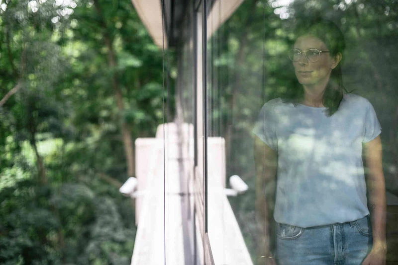 Frau schaut aus dem fenster in die natur