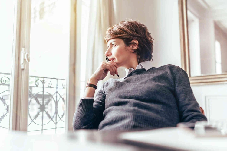 Frau sitzt in einem wei&szlig;en raum und schaut aus dem fenster