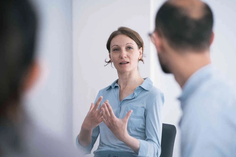 Frau spricht in einer Therapiesitzung mit zwei anderen Personen